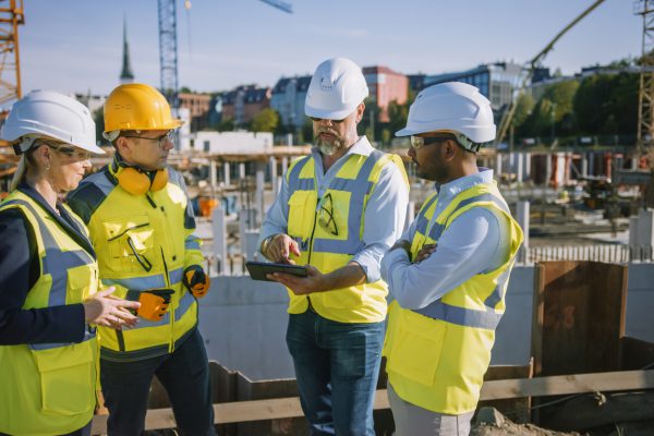 Diverse Team of Specialists Use Tablet Computer on Construction Site. Real Estate Building Project with Civil Engineer, Architect, Business Investor and General Worker Discussing Plan Details.