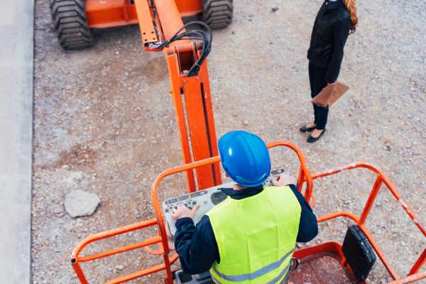 Operator In Safety Helmet controlling Straight Boom Lift